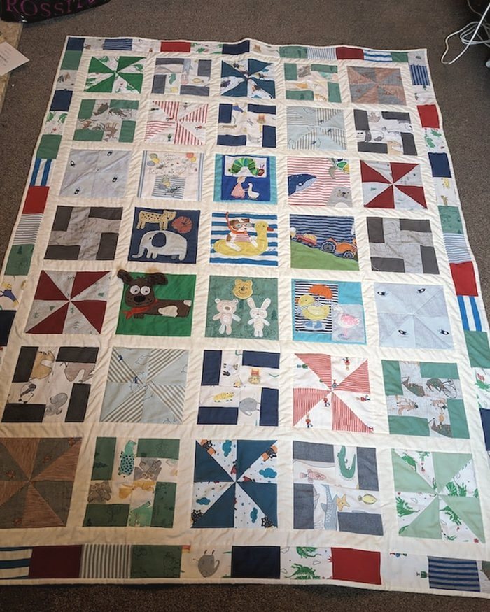 A patchwork quilt laid out, made from many different garments
